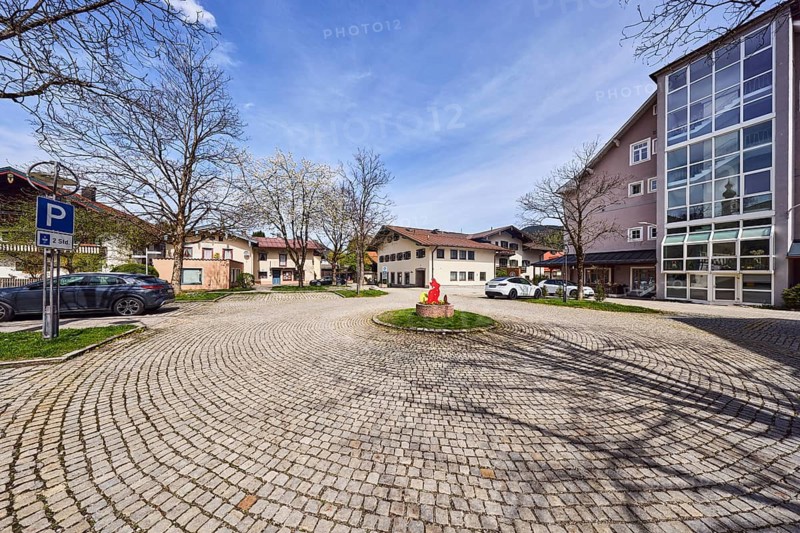 Turning loop, general architecture, alpine buildings, modern buildings, residential buildings, parking lot with cars, street made of paving stones, bare winter trees, blooming tree, blue sky, cumulus clouds, cirrostratus clouds, town hall square, Ruhpolding, district of Traunstein, Bavaria, Germany