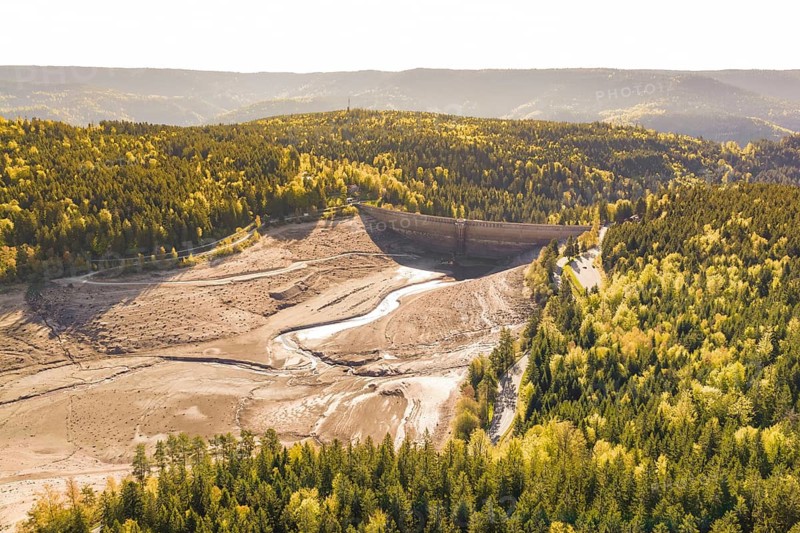 Landscape with dry riverbed and surrounding autumnal forests, emptied Schwarzenbach dam, Forbach, Black Forest, Germany