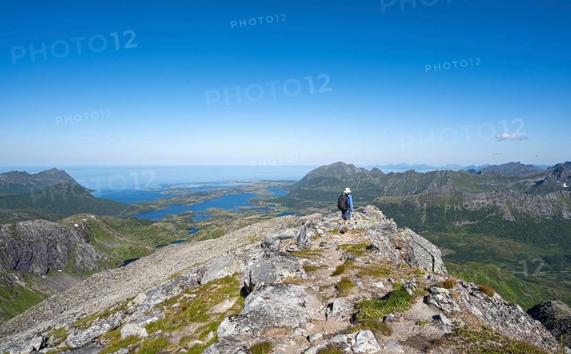 View of mountains and fjord landscape, mountaineer at the summit of Rundfjellet, Svolvaer, Nordland, Norway