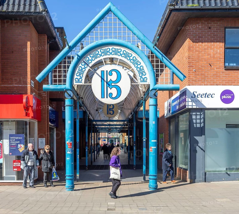 Shoppers on street with shops and entrance to The Britten Shopping centre, Lowestoft, Suffolk, England, UK