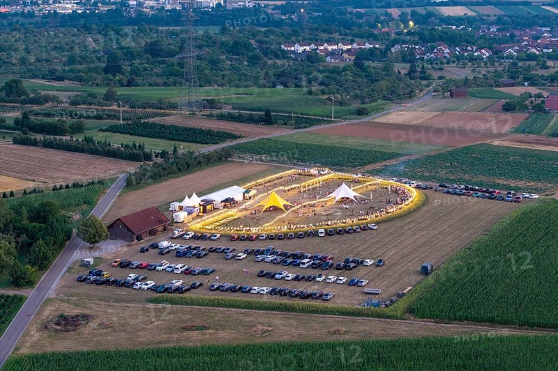 Aerial view of an illuminated festival in a field surrounded by cars and surrounding landscape, Albrecht Schwegler Winery Mountain Festival, Korb im Remstal, Baden-Württemberg, Germany