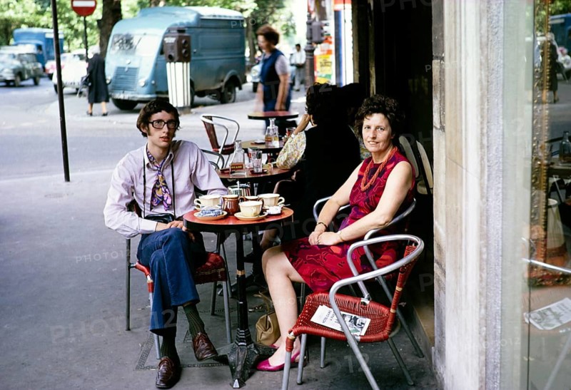 People sitting outside at a table in a street café, city centre of Paris, France, 1970