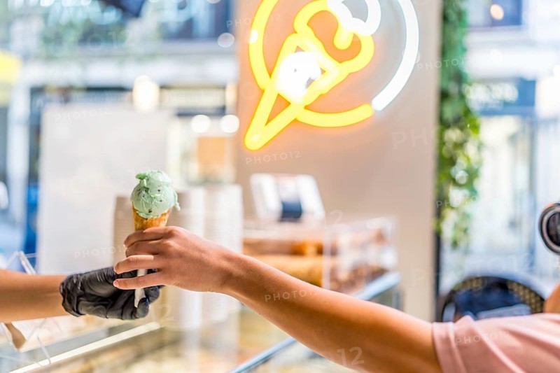 Female hand grabbing an ice cream cone from store where are shopping