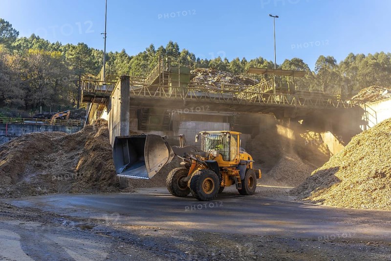 Full length wide view photo of an excavator working in the wood section of a recycling plant