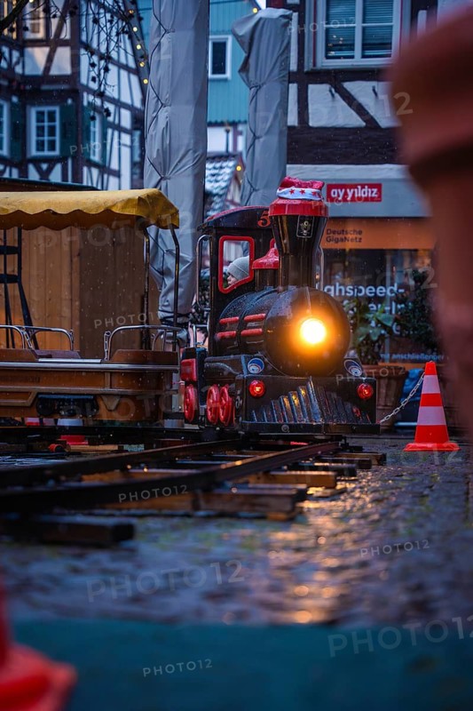 Illuminated miniature train on wet cobblestones at a Christmas market, Christmas market Calw, Black Forest, Germany