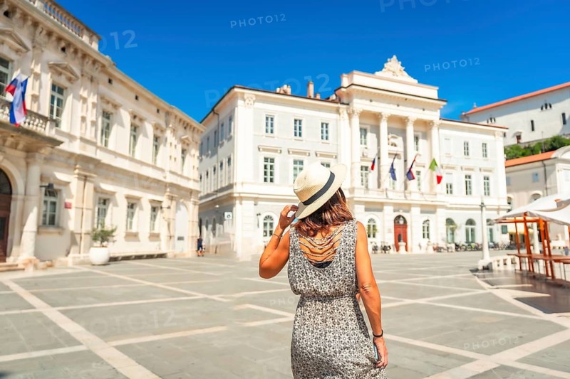 Woman enjoying summer holidays in piran, slovenia, walking in tartini square with its venetian style architecture