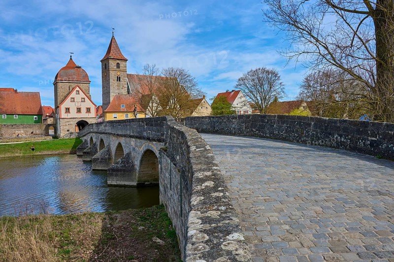 Paving stone road leads over stone bridge to a village with a characteristic church, spring, Ornbau, Triesdorf, Franconian Lake District, Ansbach district, Middle Franconia, Bavaria, Germany
