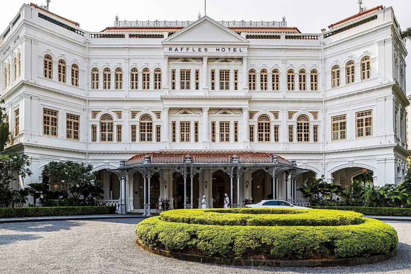 Colonial era Raffles Hotel opened by the Sarkies Brothers in 1887 fronts a manicured courtyard drive, Singapore