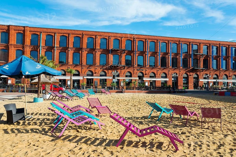 Colourful deckchairs on sand in front of a long brick building, Manufaktura, Lódz, Lodz, Lodz, Poland