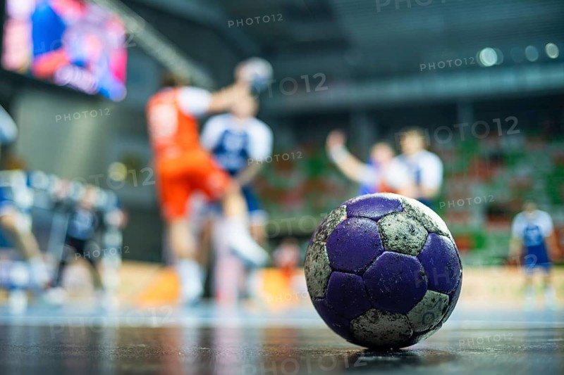 The handball ball laiyng on the parquet and handball match in the background in Lubin, Poland