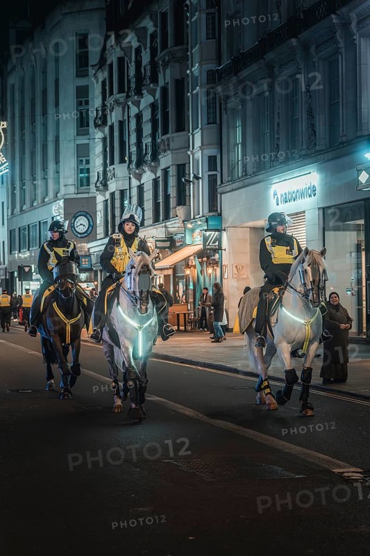 Three policemen on horses patrol Harley Street at night, New Year's Eve London, United Kingdom
