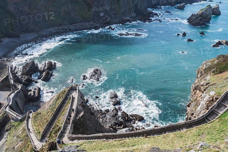 From above breathtaking view of a winding path leading to Gaztelugatxe islet, set amid the rocky coastline of Bermeo in the Basque Country, Spain