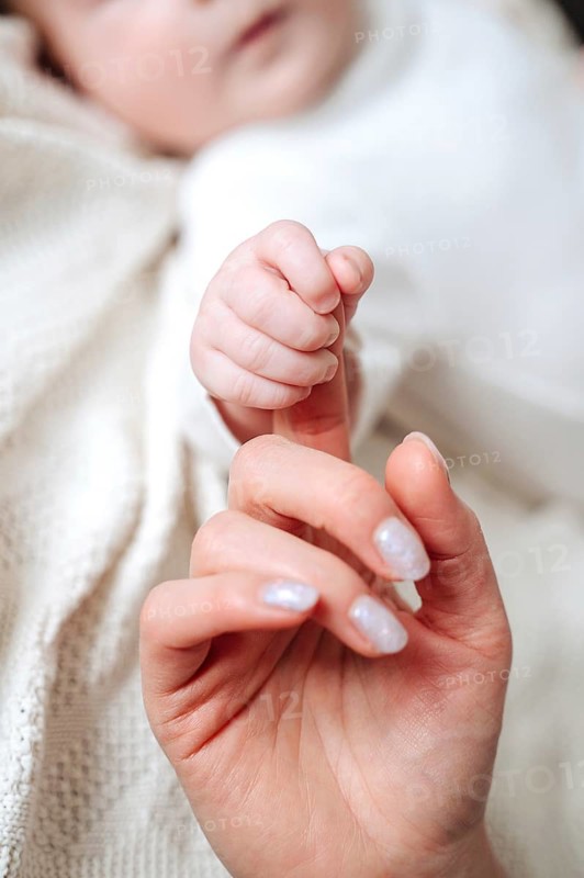 A close-up image capturing a tender moment as a mother gently holds her newborn baby girl's tiny hand. The image evokes warmth, love, and the bond between parent and child
