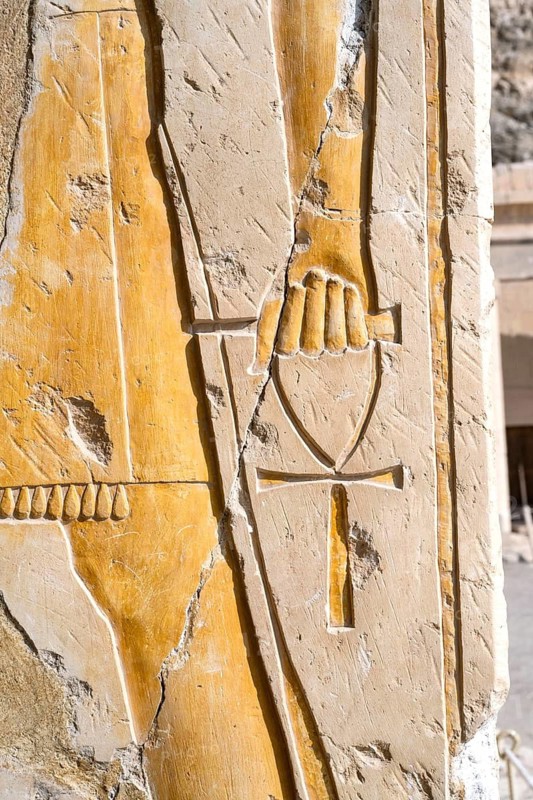 Ankh, an ancient Egyptian symbol known as the Key of Life, in a hand of a Pharaoh god on the wall of the temple of Queen Hatshepsut near Luxor, Egypt