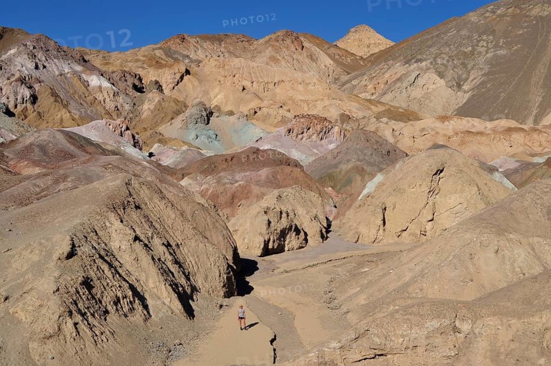 A hiker in a narrow gorge with colorful rock walls in the desert, Artist Drive, Death Valley National Park, Mojave Desert, California, Nevada, USA