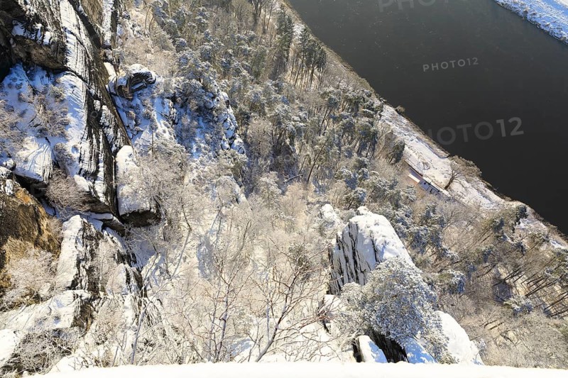Vertical view from the viewing platform of the Basteiaussicht down into the Elbe valley with snow-covered trees and rocks, Saxon Switzerland, Saxony, Germany