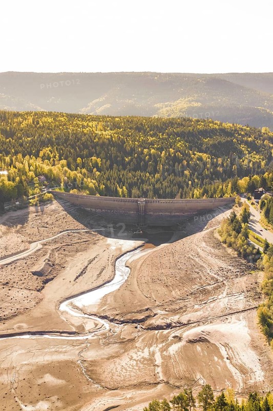 River bed under dam surrounded by autumn forest in sunshine, emptied Schwarzenbach dam, Forbach, Black Forest, Germany