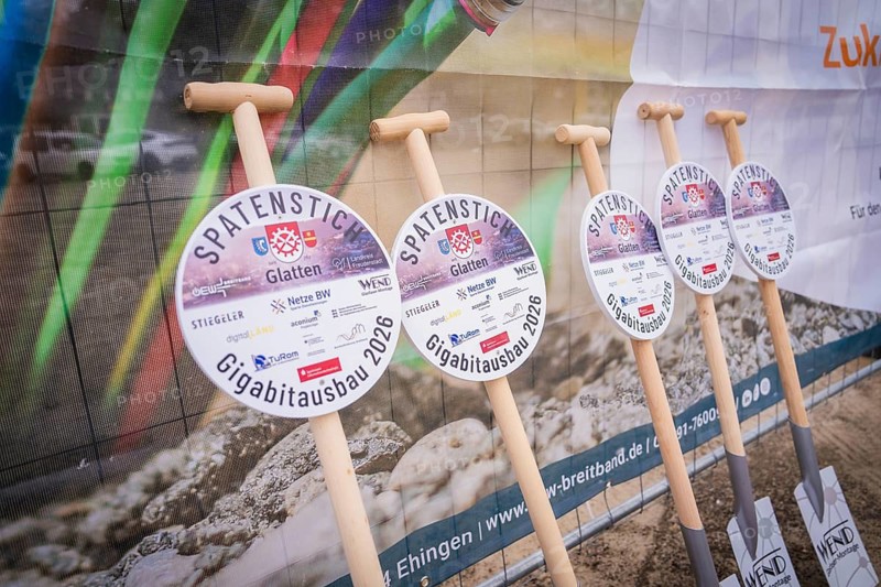 Row of shovels with decorative plaques in front of a banner with project information, fiberglass groundbreaking, Glatten, Freudenstadt district, Germany