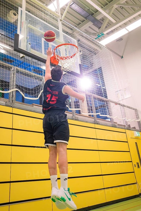 Player jumps for a dunk in a basketball game in front of a yellow wall, basketball TSV Calw, Germany
