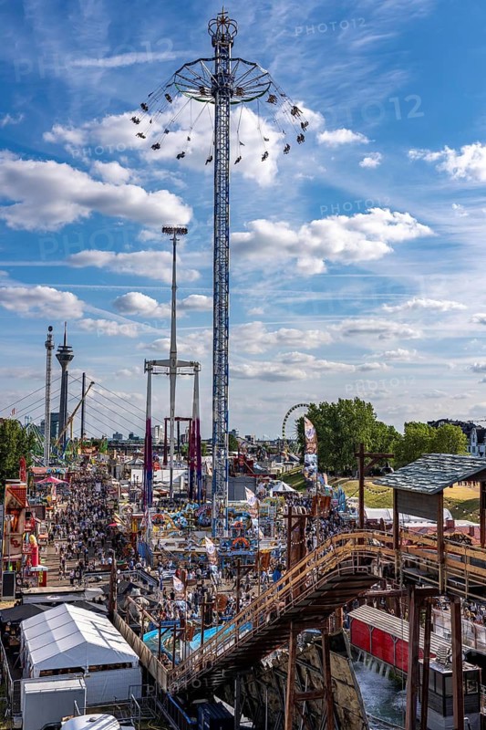 Rhine fair in the Rheinwiesen in Düsseldorf-Oberkassel, view towards the Rhine Tower, Rheinkniebrücke, rides, fairground stands, full corridors, lots of visitors, North Rhine-Westphalia, Germany