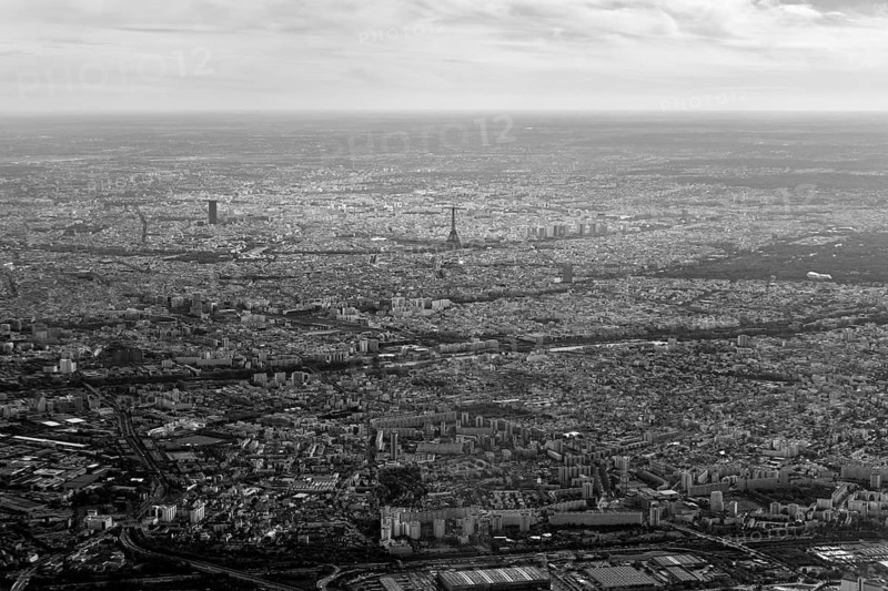 Black and white aerial view of an extensive cityscape under a cloudy sky, flight, aerial view