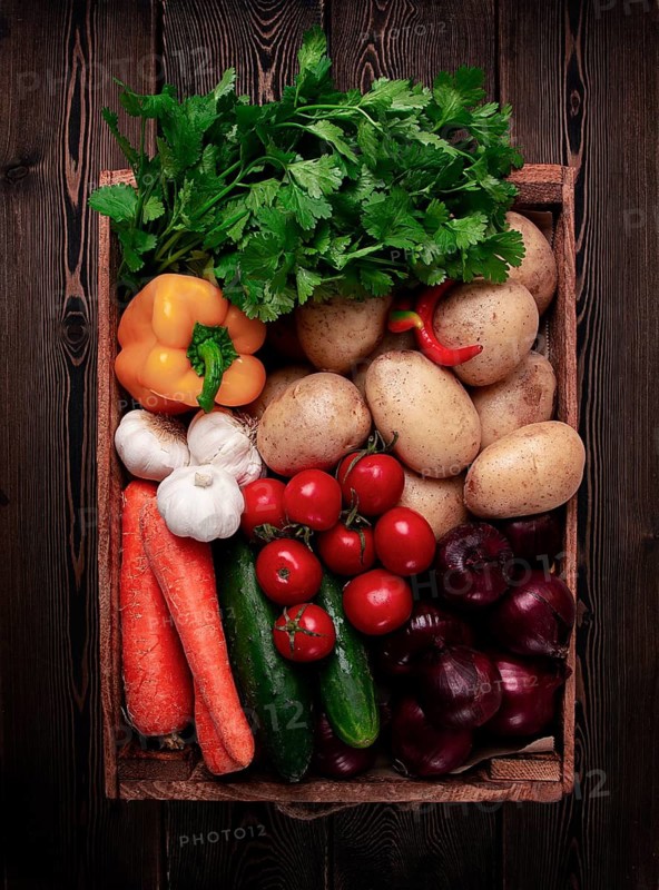 Assortment of vegetables, in a wooden food box, on a wooden table, top view, no people
