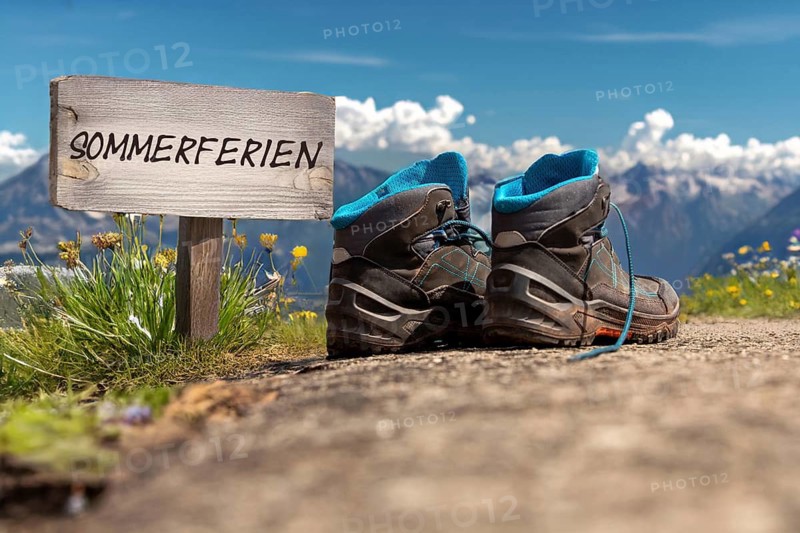 Symbolic image of company holidays/summer holidays: Hiking boots in front of an alpine backdrop and a sign with the inscription SUMMER HOLIDAYS