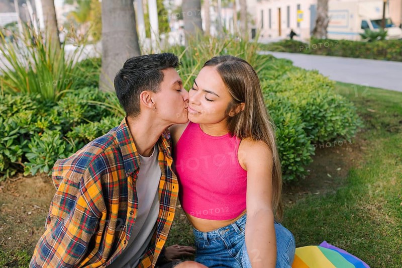 A joyful lesbian couple shares a tender kiss in a park, symbolizing love, unity, and diversity. A colorful scene that reflects the essence of LGBTQIA+ pride and inclusivity