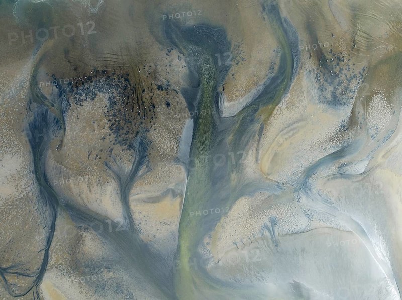 Streams and marshes at low tide in the wetlands of the Walvis Bay lagoon. In the distance Greater Flamingos (Phoenicopterus ruber). Aerial view. Drone shot. Walvis Bay, Namibia