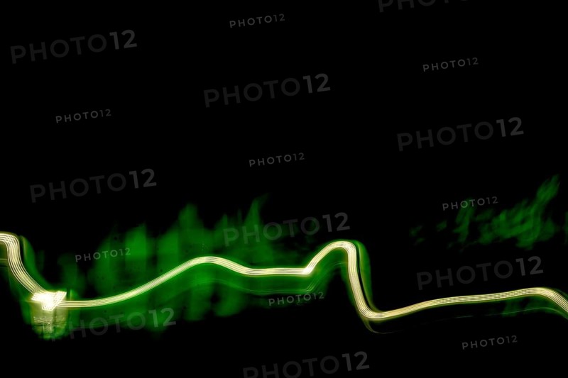 Vivid green light trails weave through a dark space, creating an abstract visual journey. The dynamic movement adds a sense of energy and fluidity to the artwork