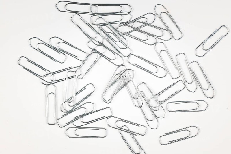 Lots of silver paper clips on a white background