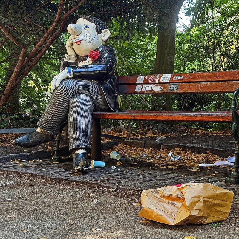 Knollennasenmann, sculpture in the style of typical Loriot drawings by Roman Strobl with painting by Patrick Przewloka, Loriotplatz with trash, Bremen, Germany