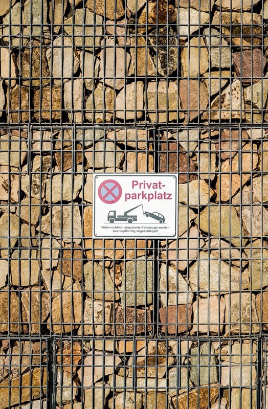 Sign on a gabion filled with stones, German for private car parking, Germany