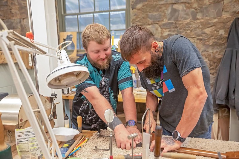 Hindman, Kentucky - Workers make high-quality guitars, dulcimers, mandolins, and ukeleles at the nonprofit Troublesome Creek Stringed Instrument Company. Most workers are recovering from an addiction. Anthony Parsons (left) and Hunter Wolford work on the neck of an instrument. Both had meth addictions