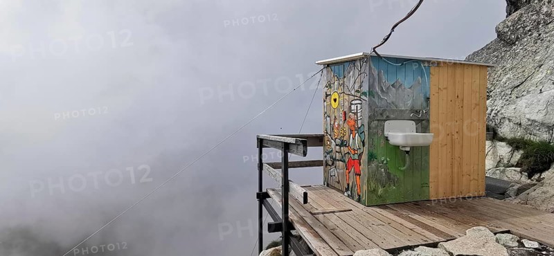 Toilet of a mountain hut, Chata pod rysmi, colorful wooden hut on a terrace with fog in the background, surrounded by mountains, hiking, Rysy, High Tatras, Slovakia