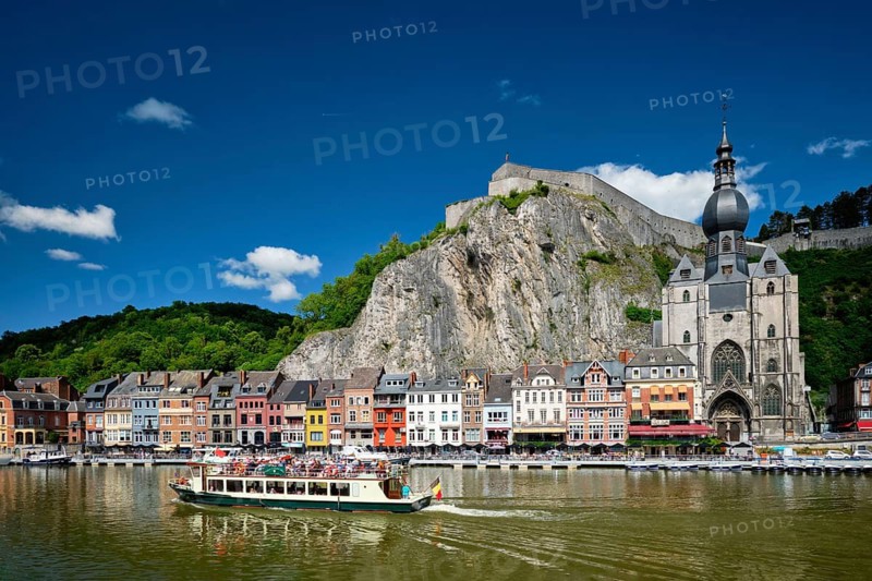 DINANT, BELIGUM, MAY 30, 2018: View of Dinant city over the Meuse river with tourist boat. Dinant is a Walloon city and municipality located on the River Meuse, in the Belgian province of Namur