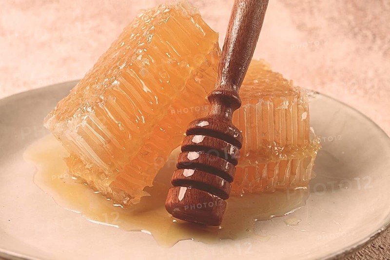 Honeycomb, with a wooden spoon-spindle, on a plate, no people