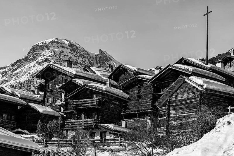Snow-covered old farmhouses, large wooden cross, black and white photo, historic town center, Grimentz, Val d'Anniviers, Valais Alps, Canton of Valais, Switzerland