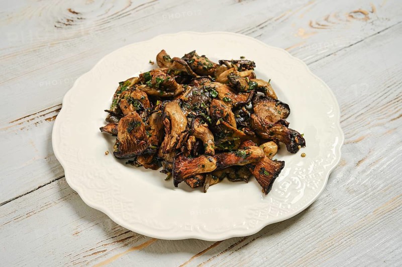 Oyster mushrooms cooked in air fryer served on white plate on wooden table