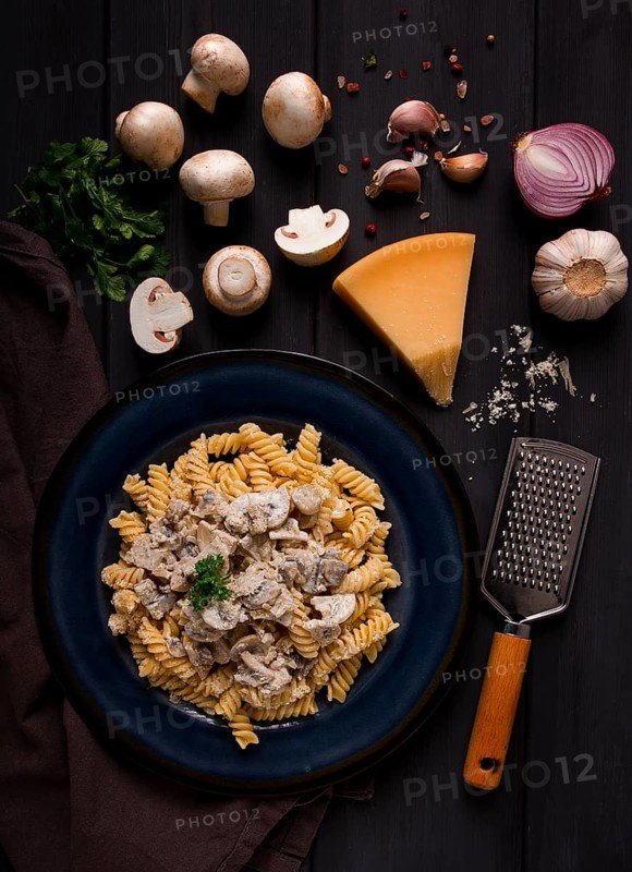 Fusilli pasta, with champignons in cream sauce, top view, with ingredients, on a wooden table, no people