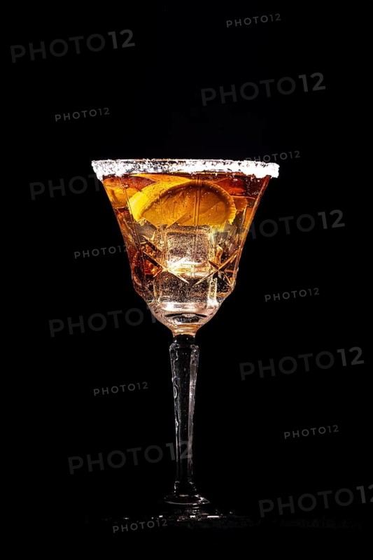 A cocktail glass with lemon slices and ice cube cubes against a black background