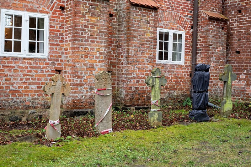 Old gravestones in front of a red brick wall with ecclesiastical windows in the background, Seemannskirche Prerow, Prerow, Mecklenburg-Vorpommern, Germany