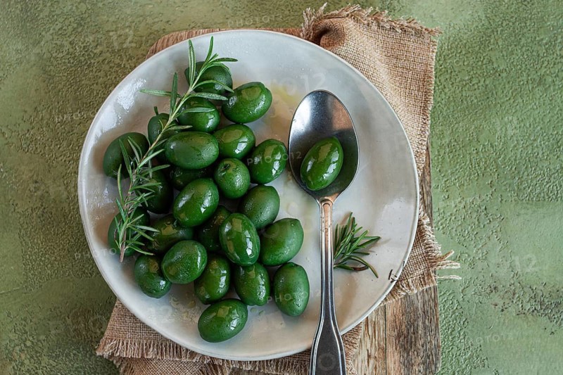 Chalkidiki olives, classic Greek green olive, on a plate, with a spoon, top view, no people