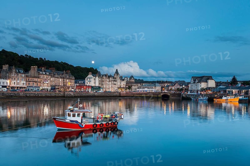 UK. Scotland. Argyll and Bute. Oban. Red fishing boat in the port of Oban with the town in the background
