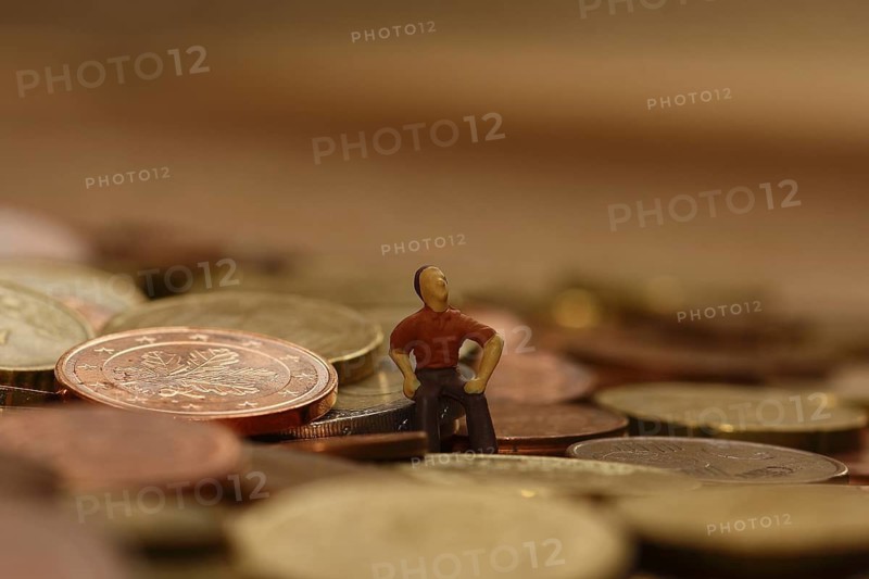 Miniature man sitting among euro coins, North Rhine-Westphalia, Germany