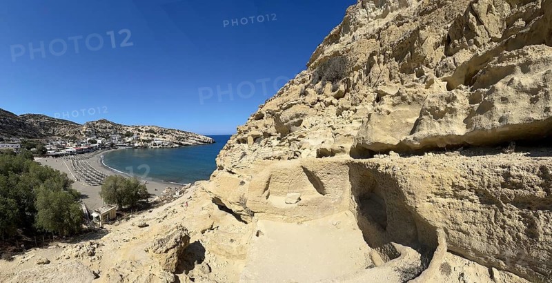 View of entrances of caves in sandstone rocks of former Roman necropolis with sandstone caves carved into sandstone Cave tombs Grottoes in rocks on the north side of Matala Bay, in the 60s and 70s hippie caves Caves for dropouts and hippies today excursion destination on the south coast of Crete island, left at the edge of the picture Libyan Sea Mediterranean, Matala, Crete, Greece