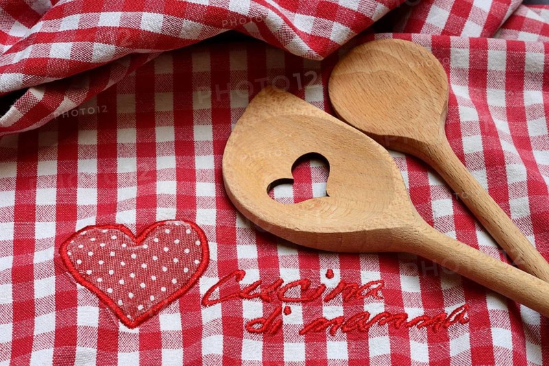 Cooking spoon on colorful kitchen towel with lettering 'Cucina di mama'