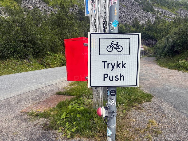 Road sign in a natural environment showing bicycle paths, with green vegetation and asphalt roads, cyclist safety in the tunnel, Senja, Troms, Norway