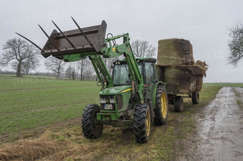Tractor and loader wagon loaded with old hay bales, Mecklenburg-Vorpommern, Germany