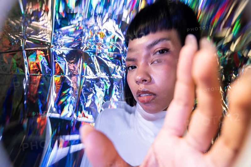 A futuristic Latin woman explores the vibrant metaverse, surrounded by a spectrum of holographic light. Her expressive gaze captures the limitless possibilities of a virtual world